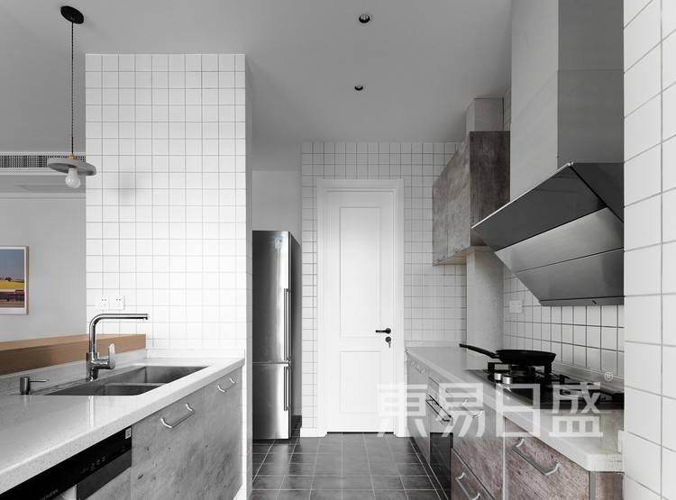 厨房的搭配以自然色位置，墙面是10*10白色小方砖，地面是30*30的黑色砖，厨柜是防水泥色的门板，厨房旁边设计了一个杂物间兼食品柜，对于居家家庭来说是一个必不可少的空间。